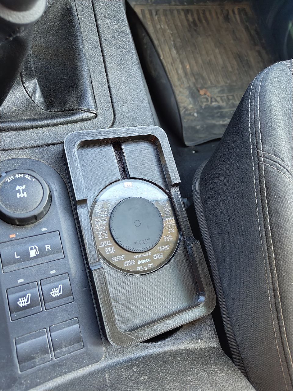 Bir fincan tutucusundaki kablosuz şarj bazusuna dayanan UAZ Patriot'ta bir telefon için bir platform. (Plastik Aparattır!!!)